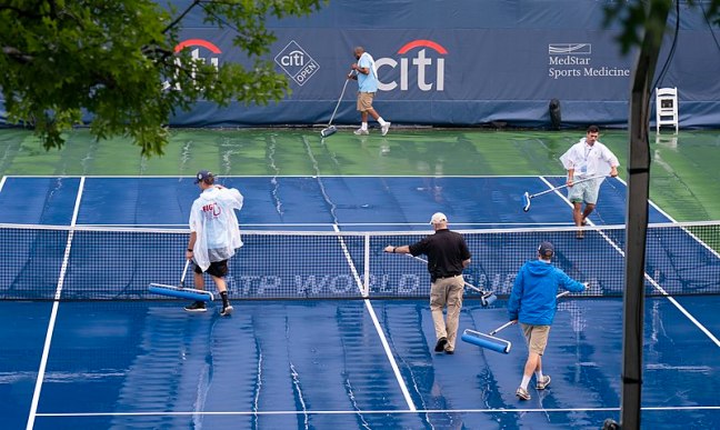 5 people removing water from a tennis court at the citi open